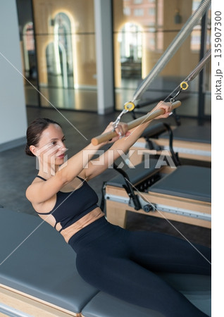 Caucasian woman doing exercises on reformer machine.  135907300