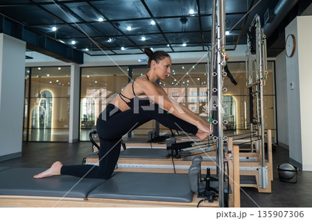 Caucasian woman doing splits on reformer. Caucasian woman doing splits on reformer. 135907306