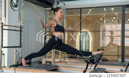 Caucasian woman doing splits on reformer. Caucasian woman doing splits on reformer. 135907307