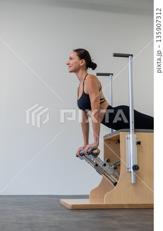 Caucasian woman doing Pilates on classic chair. 135907312