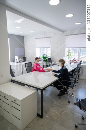 Caucasian man and woman greeting and shaking hands in office. Caucasian man and woman greeting and shaking hands in office. 135907359