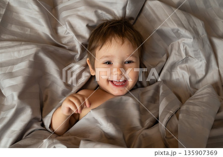 Top view of cute caucasian toddler lying in bed.  135907369