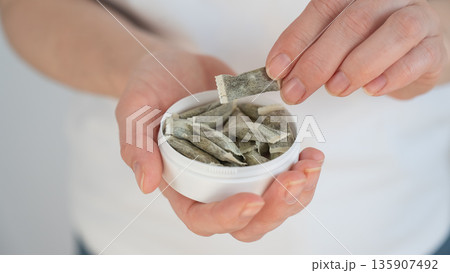 A woman holds a jar of chewing tobacco.  135907492