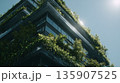Green building covered with plants in a modern city under bright sunlight during the day 135907525