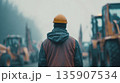 Construction worker looks at heavy machinery in a foggy environment during a morning shift 135907534