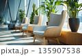 Comfortable chairs positioned near large windows with plants in a bright indoor space during daylight hours 135907538