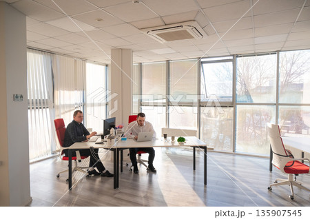 Two Caucasian men working in an office. Two Caucasian men working in an office. 135907545