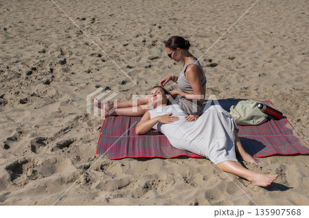 Two Caucasian women relaxing on the beach.  135907568
