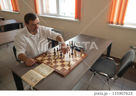 Middle aged Caucasian man playing chess.  135907628