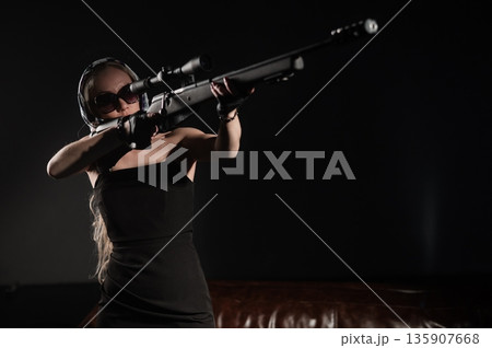 A Caucasian woman practicing shooting with a rifle and scope.  135907668
