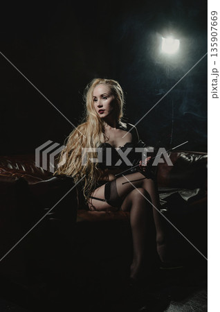 A Caucasian woman smokes from a mouthpiece while sitting on a leather sofa in her underwear. A Caucasian woman smokes from a mouthpiece while sitting on a leather sofa in her underwear. 135907669
