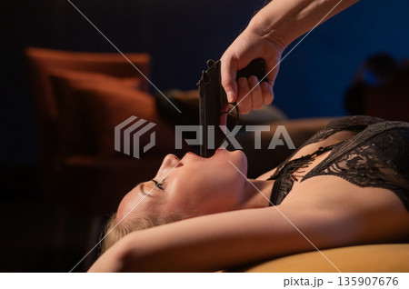 A Caucasian woman lies with a gun in her mouth. Role-playing games. A Caucasian woman lies with a gun in her mouth. Role-playing games. 135907676