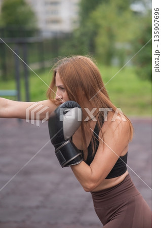 A Caucasian woman practices boxing outdoors. A Caucasian woman practices boxing outdoors. 135907696