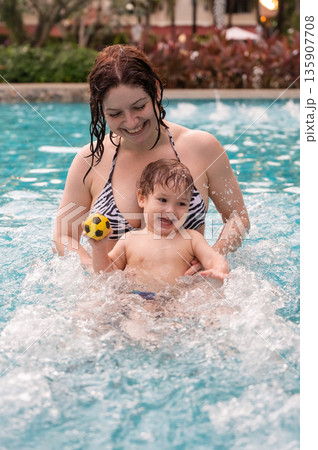 Caucasian woman holds her son while swimming in a pool on vacation. Mom teaches little boy to swim.  135907708