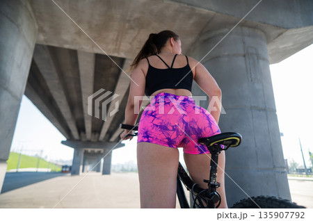 Caucasian woman in short shorts riding a bicycle.  135907792