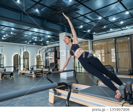 Caucasian woman doing side bends on reformer machine.  135907806