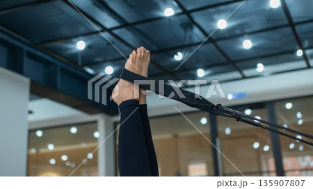 Caucasian woman doing exercises on reformer machine. Caucasian woman doing exercises on reformer machine. 135907807