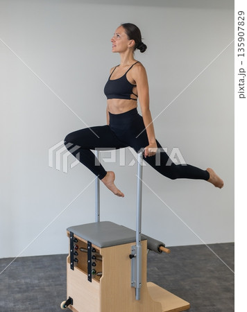 Caucasian woman doing Pilates on classic chair. 135907829