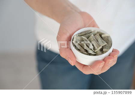 A woman holds a jar of chewing tobacco.  135907899