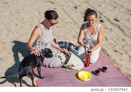Two Caucasian women on a picnic on the beach. Two Caucasian women on a picnic on the beach. 135907942