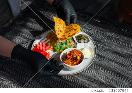 A chef wearing black gloves prepares fajitas. A chef wearing black gloves prepares fajitas. 135907945