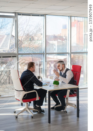 Two Caucasian men communicating at a business meeting. Two Caucasian men communicating at a business meeting. 135907949