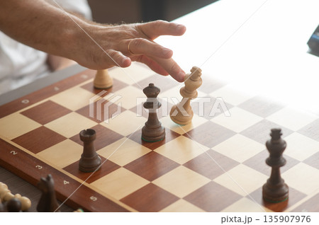 Close up of hands of middle aged caucasian man playing chess.  135907976
