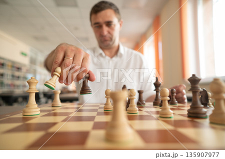 Middle aged Caucasian man playing chess.  135907977