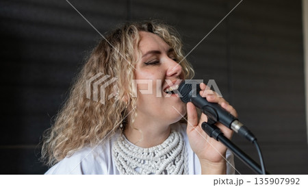 Caucasian woman singing into microphone in music studio.  135907992