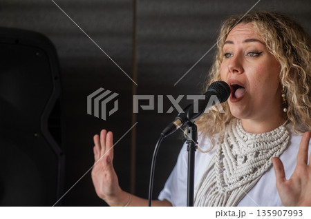 Caucasian woman singing into microphone in music studio.  135907993