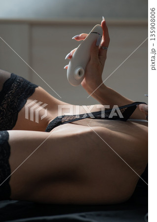 A woman holds a vacuum vibrator near her panties..  135908006