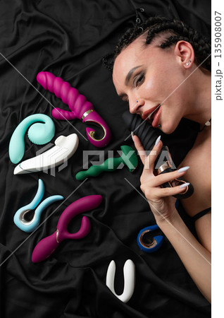 Portrait of Caucasian woman lying on bed among sex toys. Portrait of Caucasian woman lying on bed among sex toys. 135908007