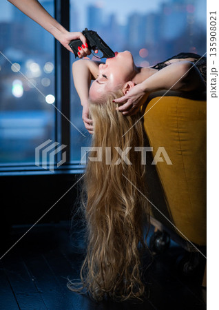 A Caucasian woman lies with a gun in her mouth. Role-playing games. A Caucasian woman lies with a gun in her mouth. Role-playing games. 135908021