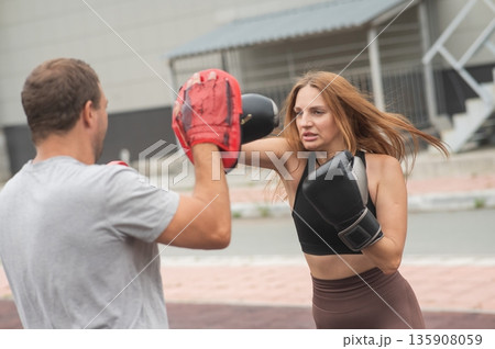 Man and woman sparring outdoors. Boxing lesson. 135908059