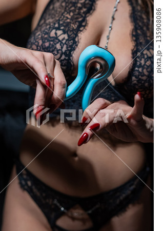 A woman in black lingerie holds a curved vibrator.  135908086