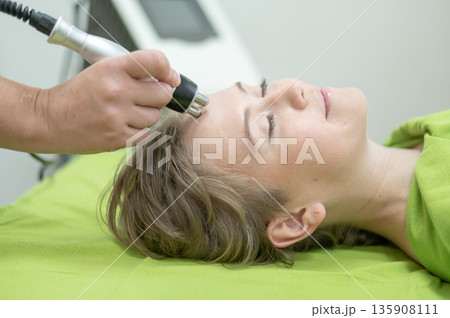 Caucasian woman undergoing radio wave RF lifting procedure in beauty salon.  135908111