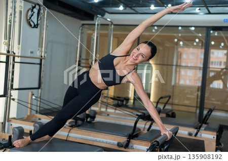 Caucasian woman doing side bends on reformer machine.  135908192