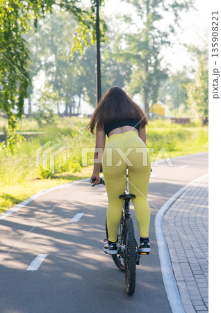 Curvy Caucasian Woman Riding Bicycle in Park. Curvy Caucasian Woman Riding Bicycle in Park. 135908221