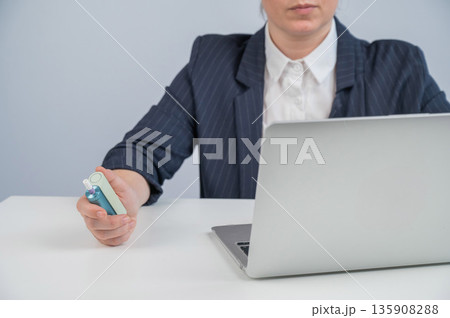 Business woman smoking an electronic cigarette while working on a laptop. Tobacco heating system.  135908288