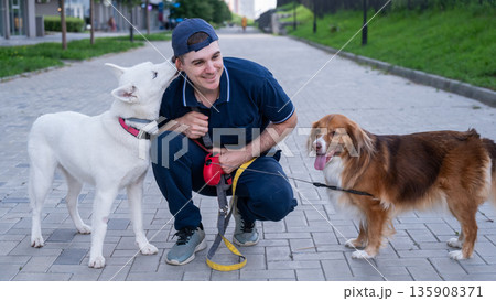 A man hugs his two dogs while on a walk.  135908371