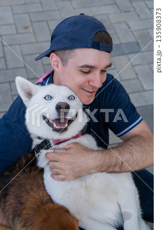 A man hugs his dog on a walk.  135908373