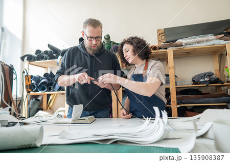 A man and a woman work as tanners in a workshop.  135908387