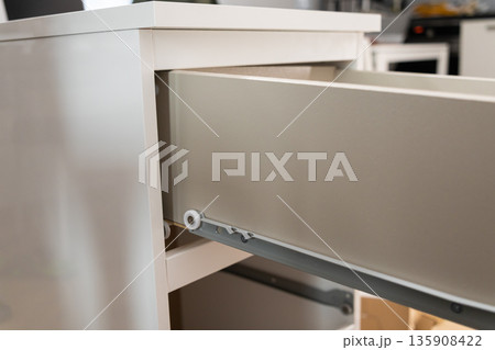 A pristine white open drawer revealing its precise roller mechanism, highlighting modern furniture construction, efficient storage solutions, and home interior design A pristine white open drawer revealing its precise roller mechanism, highlighting modern furniture construction, efficient storage solutions, and home interior design 135908422