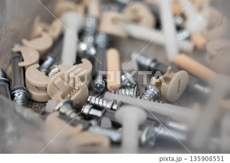 Various furniture assembly hardware components including screws, wooden dowels, and cam locks, essential for DIY home projects and product construction Various furniture assembly hardware components including screws, wooden dowels, and cam locks, essential for DIY home projects and product construction 135908551