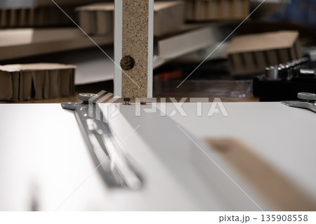 Assembling a modern flat-pack furniture panel, demonstrating the efficient use of a wooden dowel and metal cam lock system for quick and simple DIY home improvement 135908558