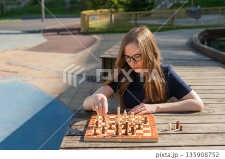 Caucasian woman playing chess outdoors. Caucasian woman playing chess outdoors. 135908752