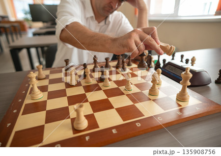 Close up of hands of middle aged caucasian man playing chess.  135908756