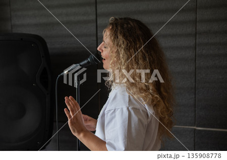 Caucasian woman singing into microphone in music studio.  135908778
