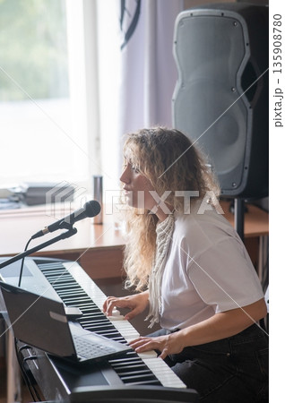 Caucasian woman singing into microphone and playing synthesizer. Online lesson on laptop. Caucasian woman singing into microphone and playing synthesizer. Online lesson on laptop. 135908780