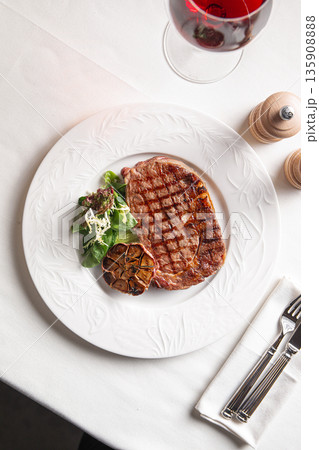 Grilled beef steak with roasted garlic and greens 135908888
